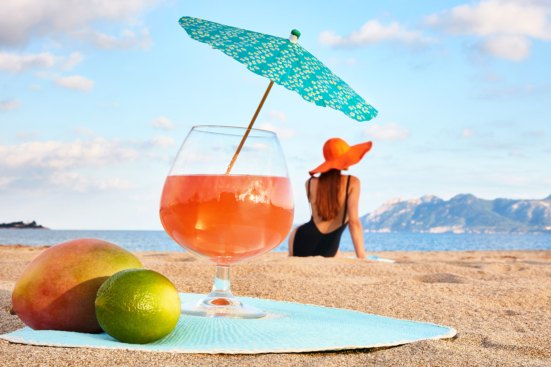 Jeune fille de dos sur une plage de Majorque, verre cocktail en premier plan