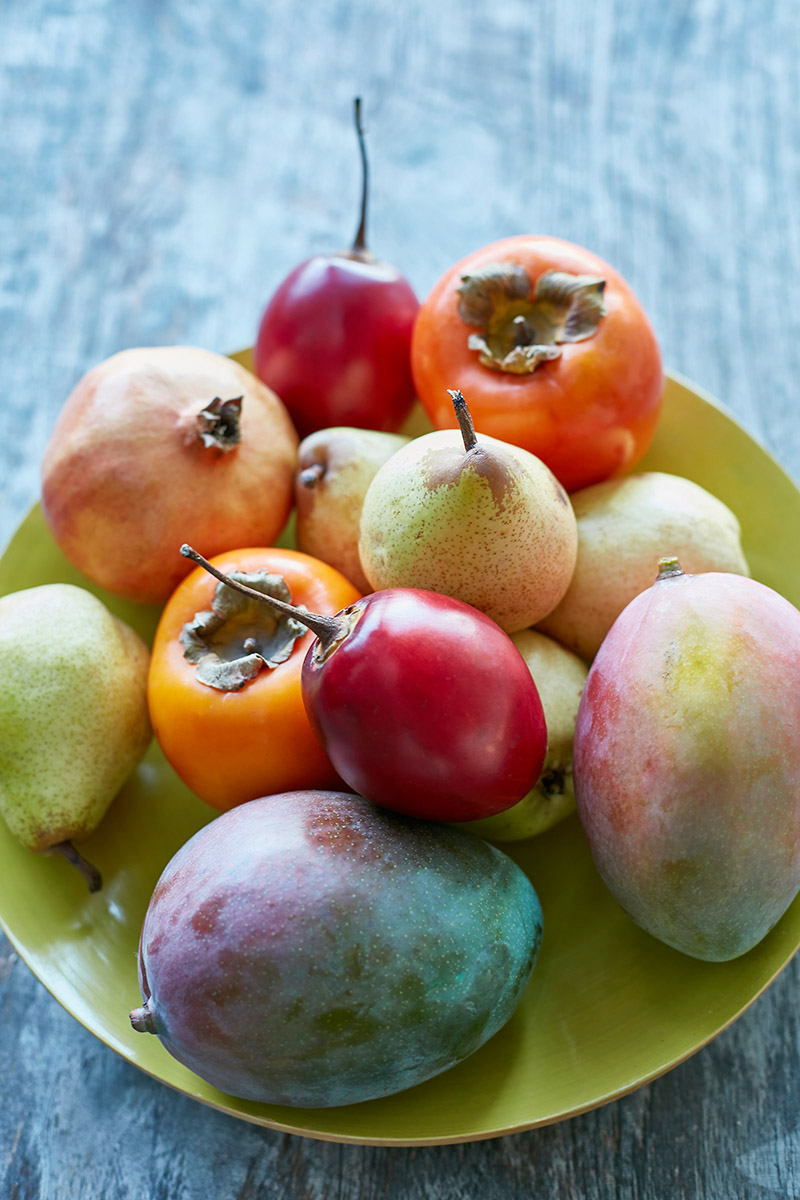 Assiette de fruits colorés : tamarillos, mangues, kaki, poires, grenade