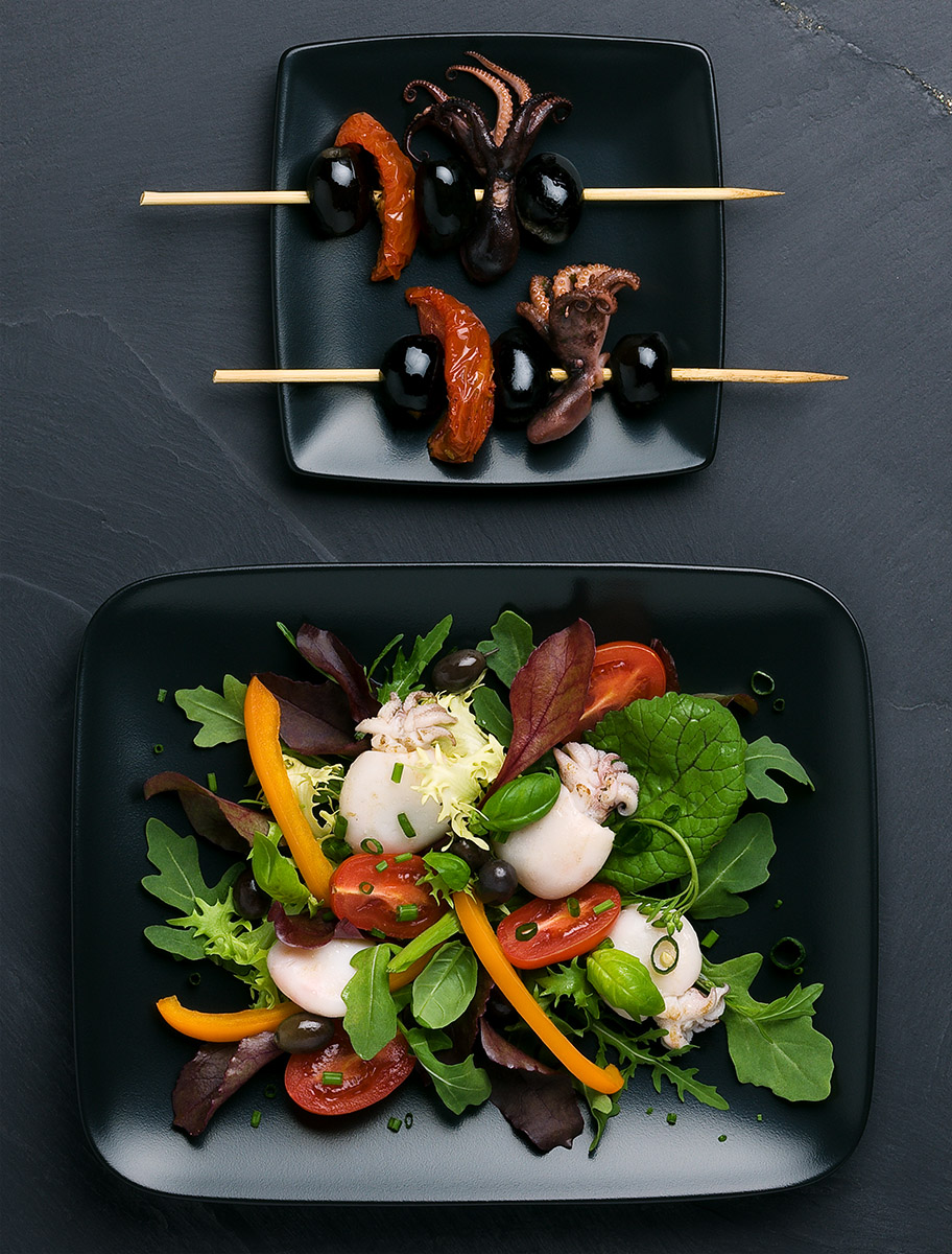 Assiette de salade : tomates roquette poivrons calamar mâche et brochettes de calamars