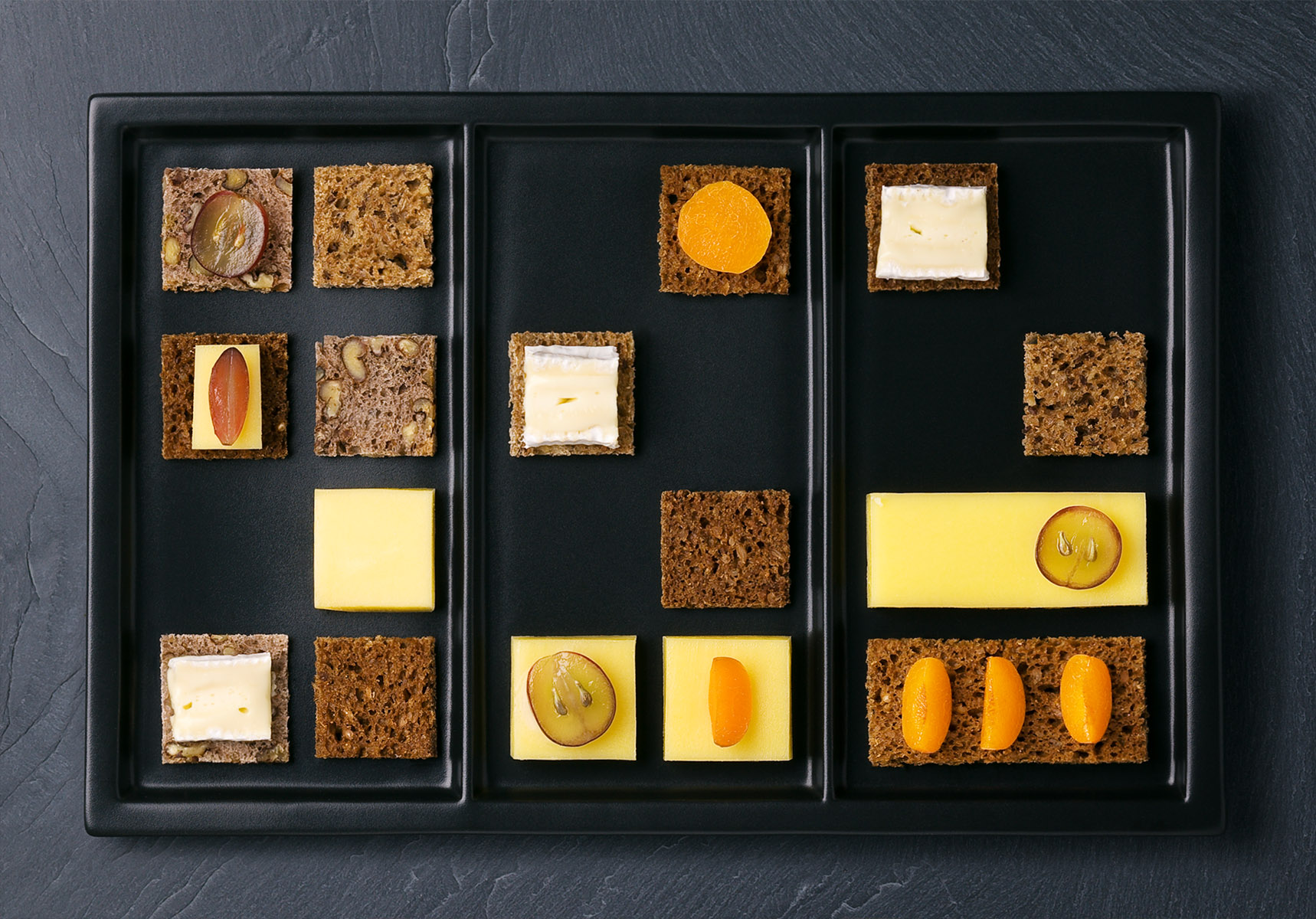 Plateau géométrique de toasts de fromages, fruit et raisins