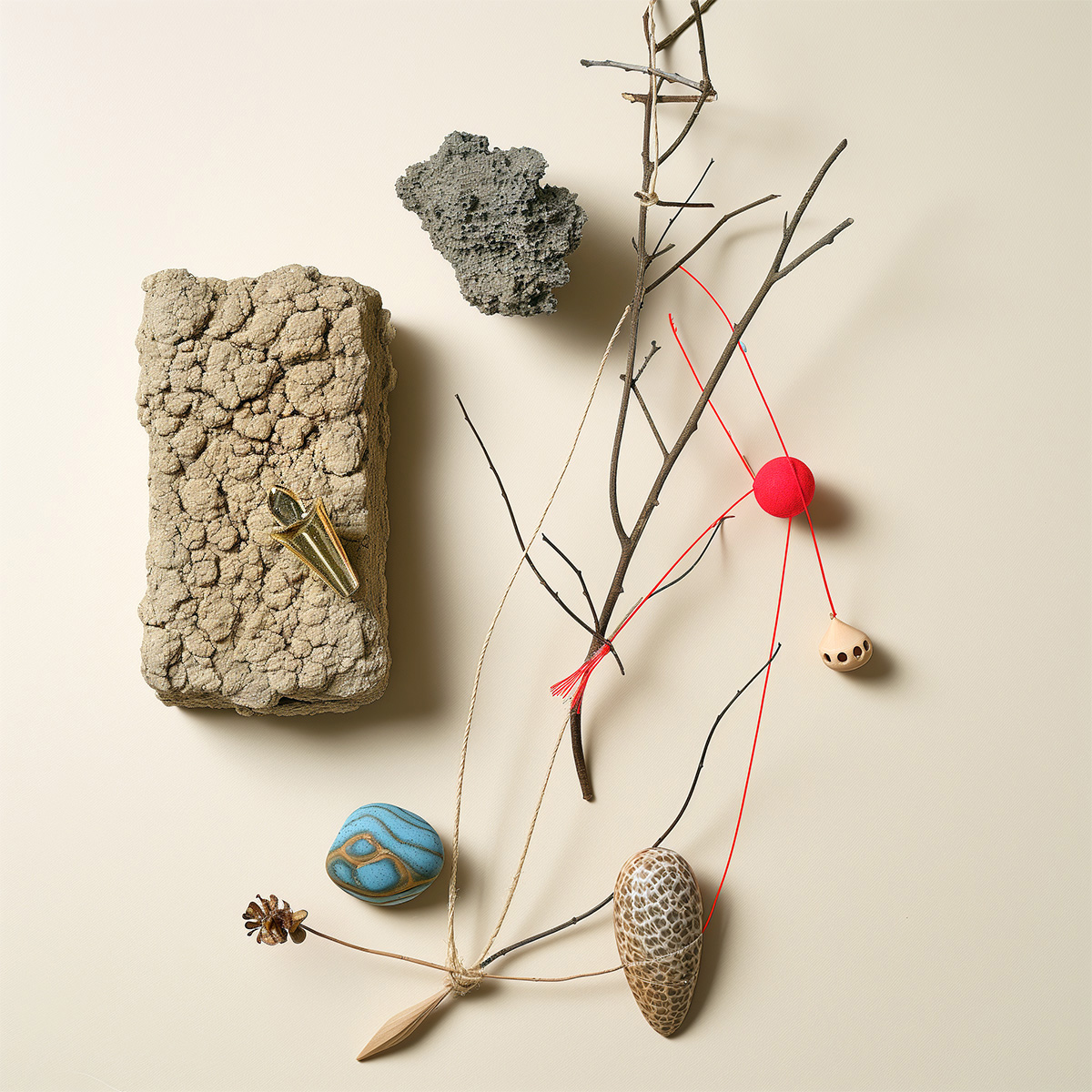 A graphic still life with stones, various unreal colored objects, beige background