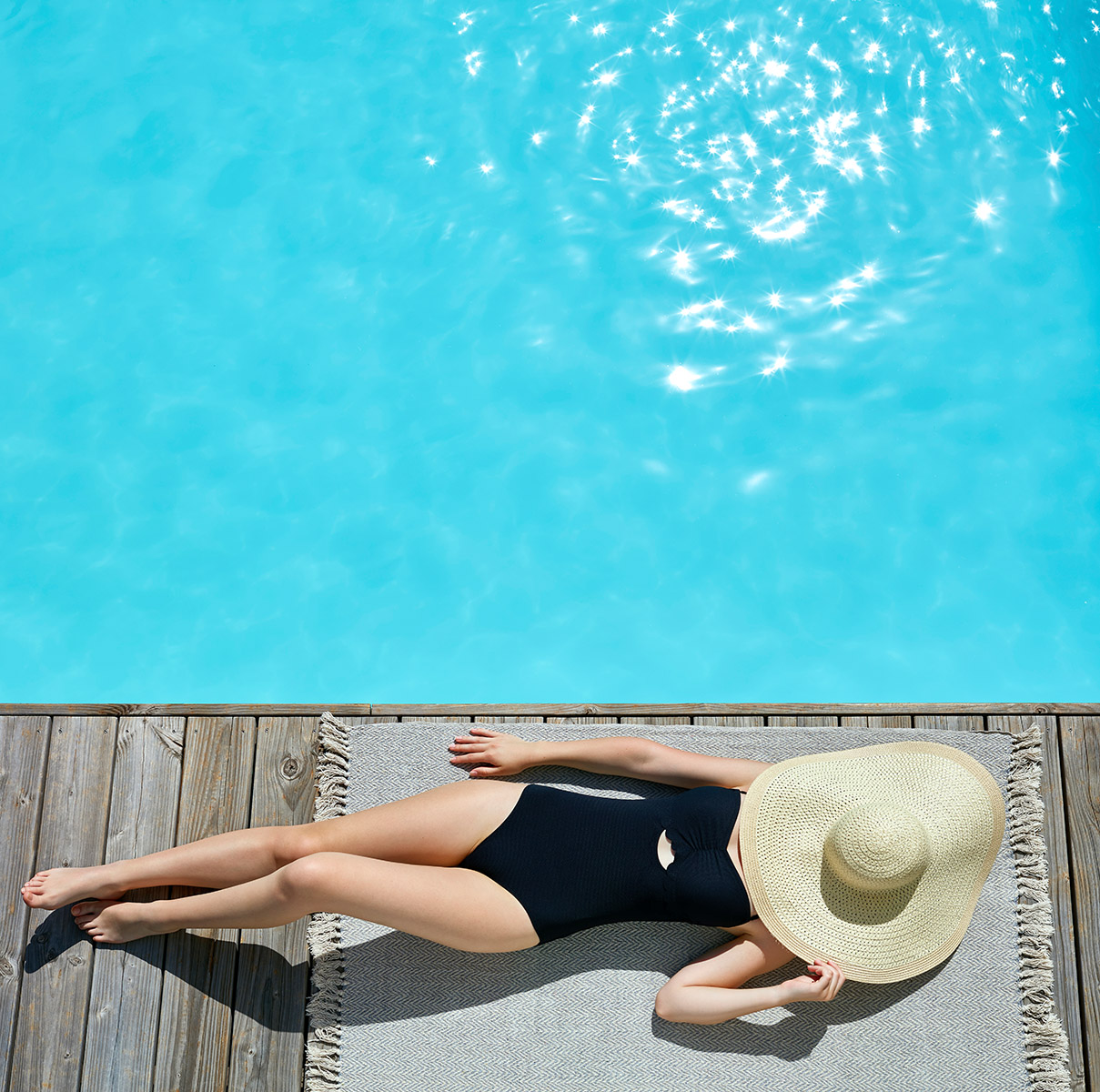 Jeune fille en maillot de bain noir allongée au bord d'une piscine