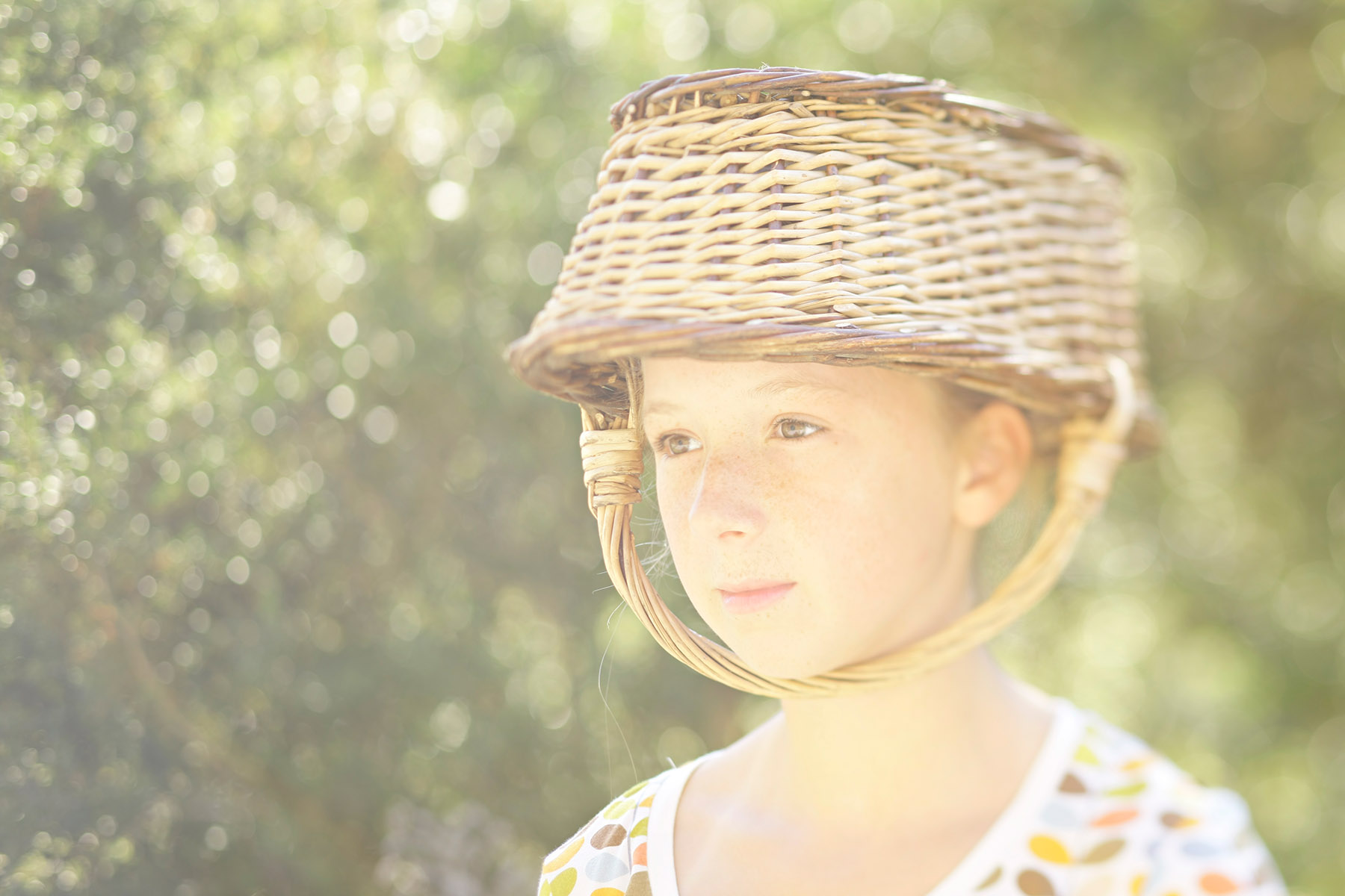 Portrait jeune fille avec un panier d'osier en guise de chapeau